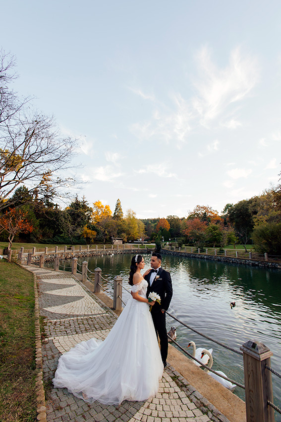 Zeynep’in gelinliği, kasrın taş duvarları arasında bir masal gibi süzülürken Ali’nin bakışlarında tek bir cümle vardı: “İyi ki.” Abartısız, gösterişsiz ama çok derin… İşte gerçek aşk tam da böyle bir şeydi. Poz vermek hiç gerekmedi; onlar yan yana durdukça anlar kendiliğinden oluştu. Gülüşler içtendi, dokunuşlar sakindi, her karede güven vardı. Hidiv Kasrı’ndaki çekim, hikâyenin ağırbaşlı başlangıcı gibiydi. Ardından Atatürk Arboretumu’na doğru yola çıktık. Sonbaharın sarıdan altına dönen renkleri, göl kenarında sessizce süzülen kuğular, yaprakların altında kalan patikalar… Doğa, sanki bu aşka özel hazırlanmıştı. Zeynep ve Ali yürüdükçe ışık onları takip etti, ağaçlar başlarını eğip bu mutluluğa tanıklık etti. Atatürk Arboretumu’nda çekilen her karede biraz huzur, biraz heyecan, çokça sevgi vardı. Gelinliğin etekleri yapraklara karıştı, kahkahalar dalların arasından yankılandı. Kimse acele etmedi. Çünkü bazı anlar çabuk geçmesin diye yavaş yaşanır. Benim için düğün fotoğrafçılığı, sadece güzel kareler yakalamak değil; o günün ruhunu, çiftlerin birbirine baktığında hissettiklerini yıllar sonrasına taşıyabilmek. Zeynep ve Ali çekim sonunda yanımdan ayrılırken yüzlerinde aynı ifade vardı: Hafiflemiş, mutlu ve tamamlanmış… İstanbul’da düğün fotoğrafı çektirmek isteyen her çift için Hidiv Kasrı ve Atatürk Arboretumu hâlâ en özel duraklardan. Ama asıl güzellik, oraya götürdüğünüz hikâyede saklı. Doğru ışık, doğru an ve samimi bir bağ bir araya geldiğinde ortaya çıkan şey, sadece fotoğraf değil; bir hatıradır.