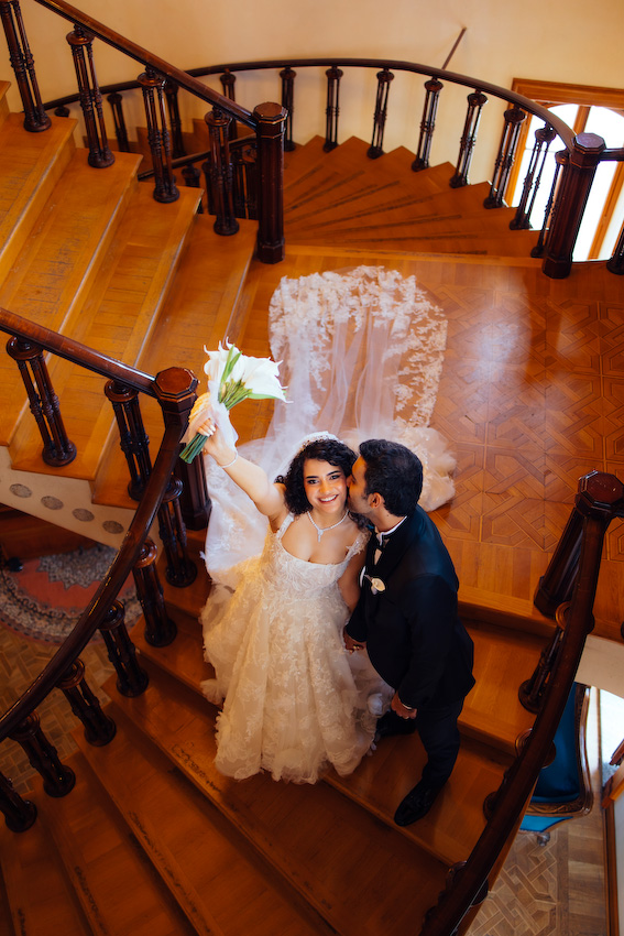 Adile Sultan Kasrı büyük salonunda avizenin altında poz veren İmran ve Burak düğün fotoğraf çekimi