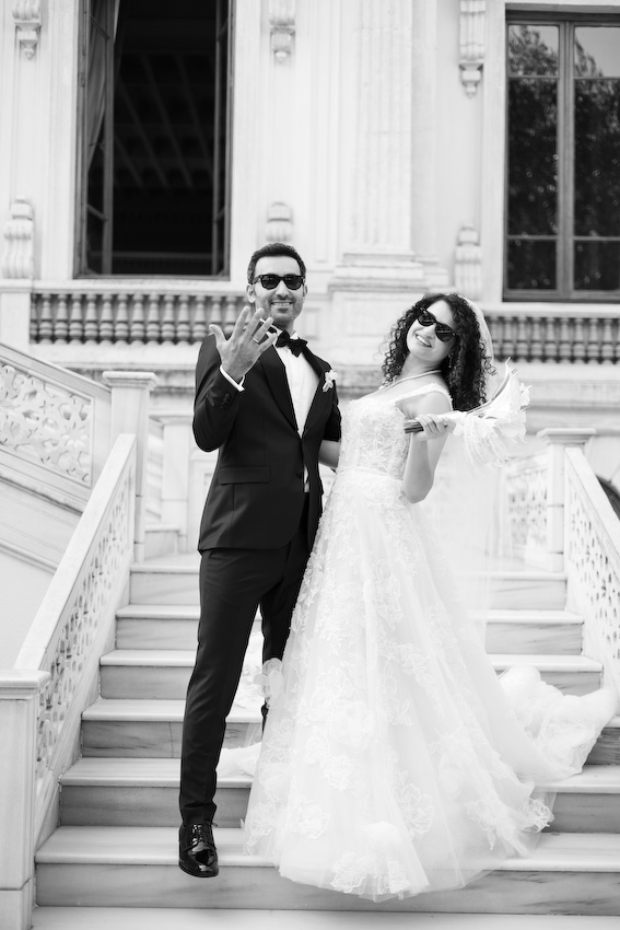 Adile Sultan Kasrı büyük salonunda avizenin altında poz veren İmran ve Burak düğün fotoğraf çekimi