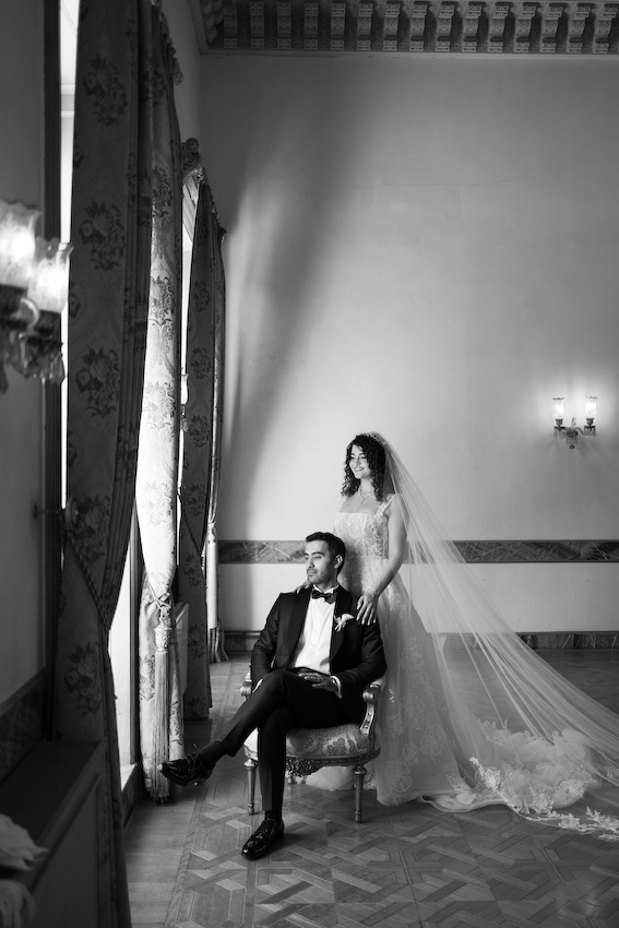 Adile Sultan Kasrı büyük salonunda avizenin altında poz veren İmran ve Burak düğün fotoğraf çekimi